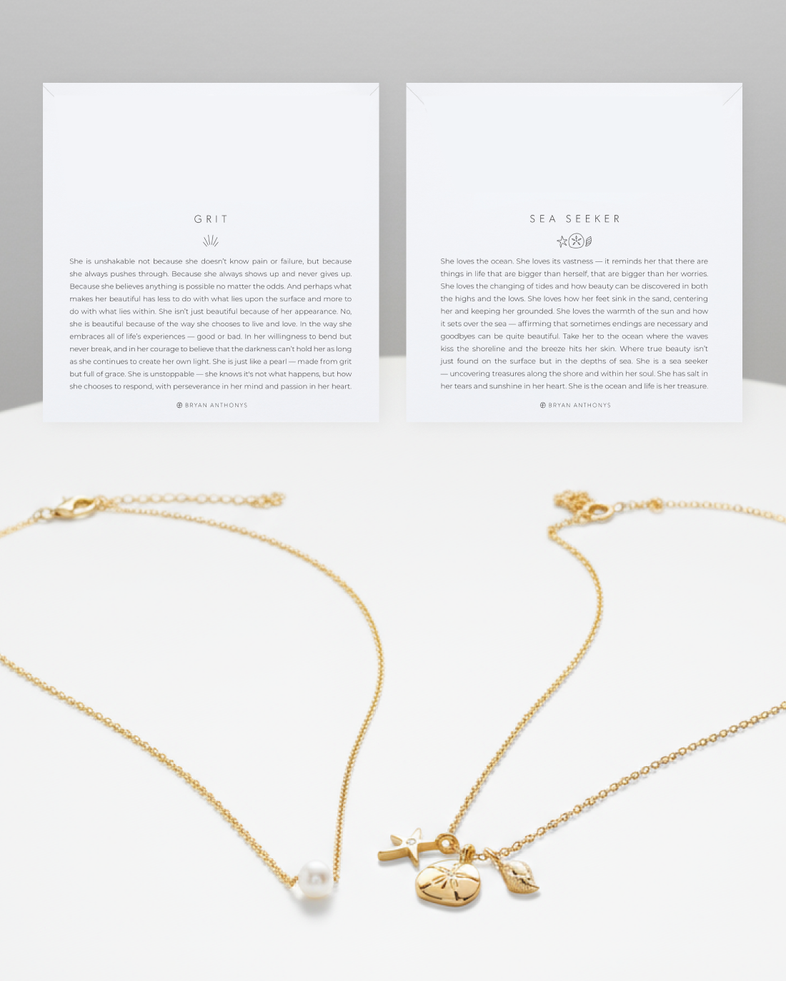 wo white cards, one titled 'GRIT' (left) and one titled 'SEA SEEKER' (right), sit above two gold chain necklaces that are layered together. The top necklace has a small pearl pendant, and the bottom necklace has a cluster of ocean-themed charms.