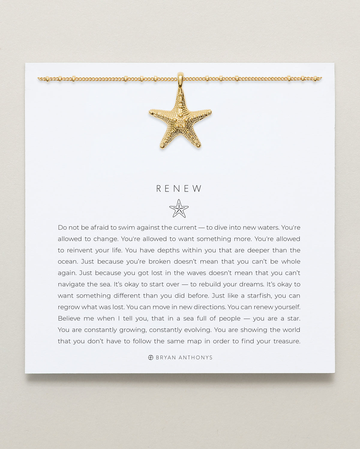 A gold bead chain necklace with a detailed, textured starfish pendant hangs from the top edge of a white card. The card features the title 'RENEW' and an inspirational message about embracing change.
