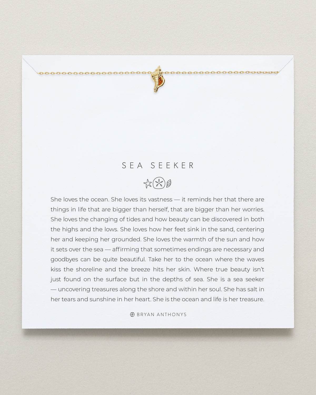 A gold ball chain necklace featuring a small, textured golden conch shell icon pendant hangs from the top edge of a white card.