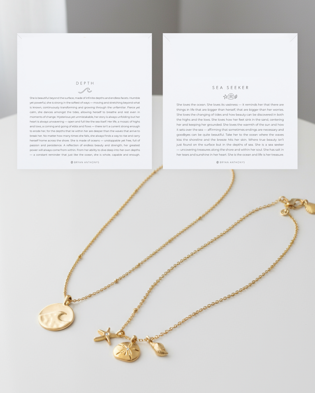 wo white cards, one titled 'DEPTH' (left) and one titled 'SEA SEEKER' (right), sit above two gold chain necklaces. The left necklace has a round charm with a crescent moon, and the right necklace has a cluster of ocean-themed charms (starfish, sand dollar, shell).