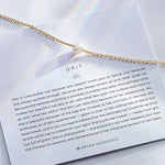 grit necklace in gold on with description card