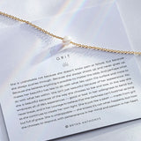 grit necklace in gold on with description card