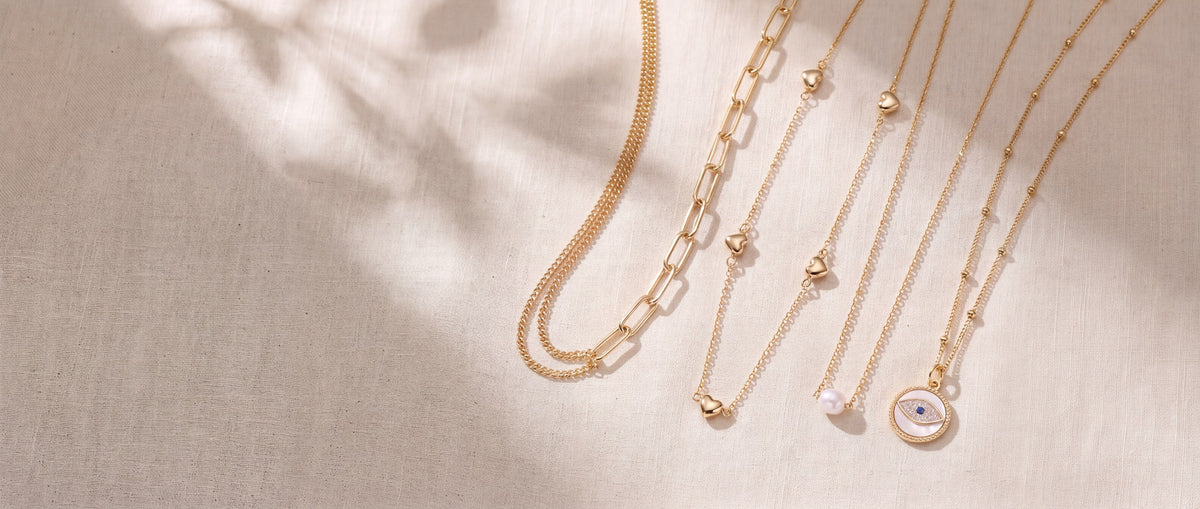 Through It All, Steady Heart, Grit and Side Eye necklaces laid flat on cream linen