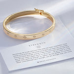 Strength Hinged Bracelet showcase in 14k gold on card